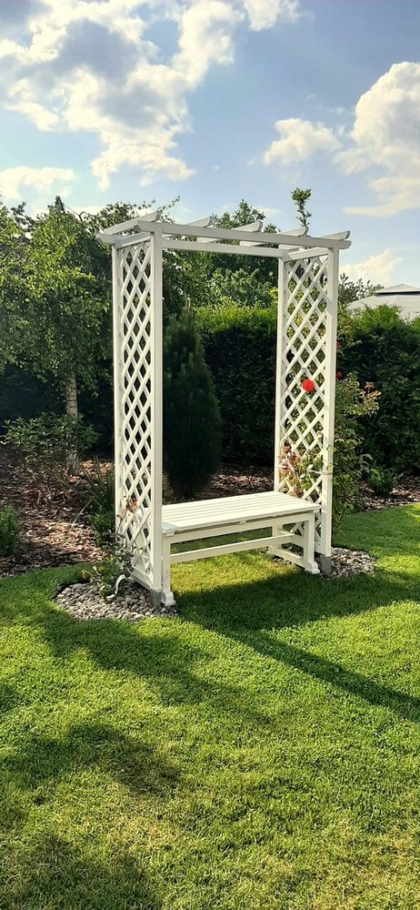 Biała pergola z ławką w ogrodzie